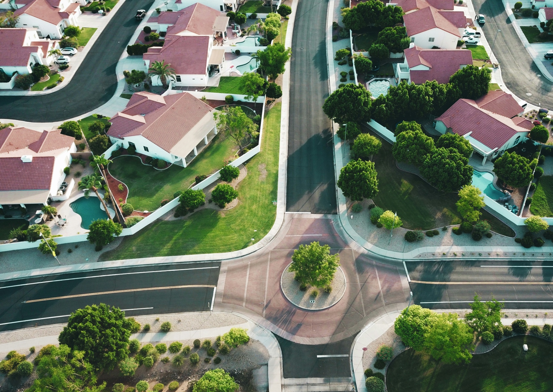 Aerial view of a residential neighborhood with homes, lawns, and a roundabout